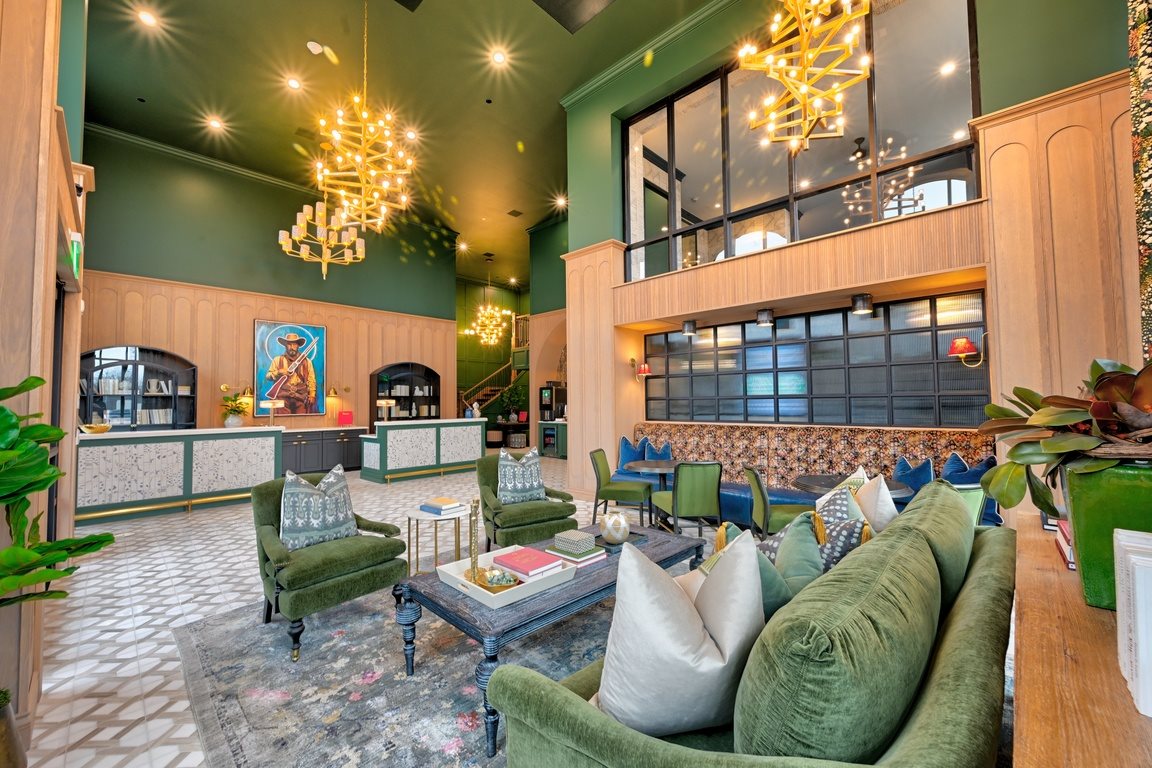 A living room with a green couch and a chandelier.